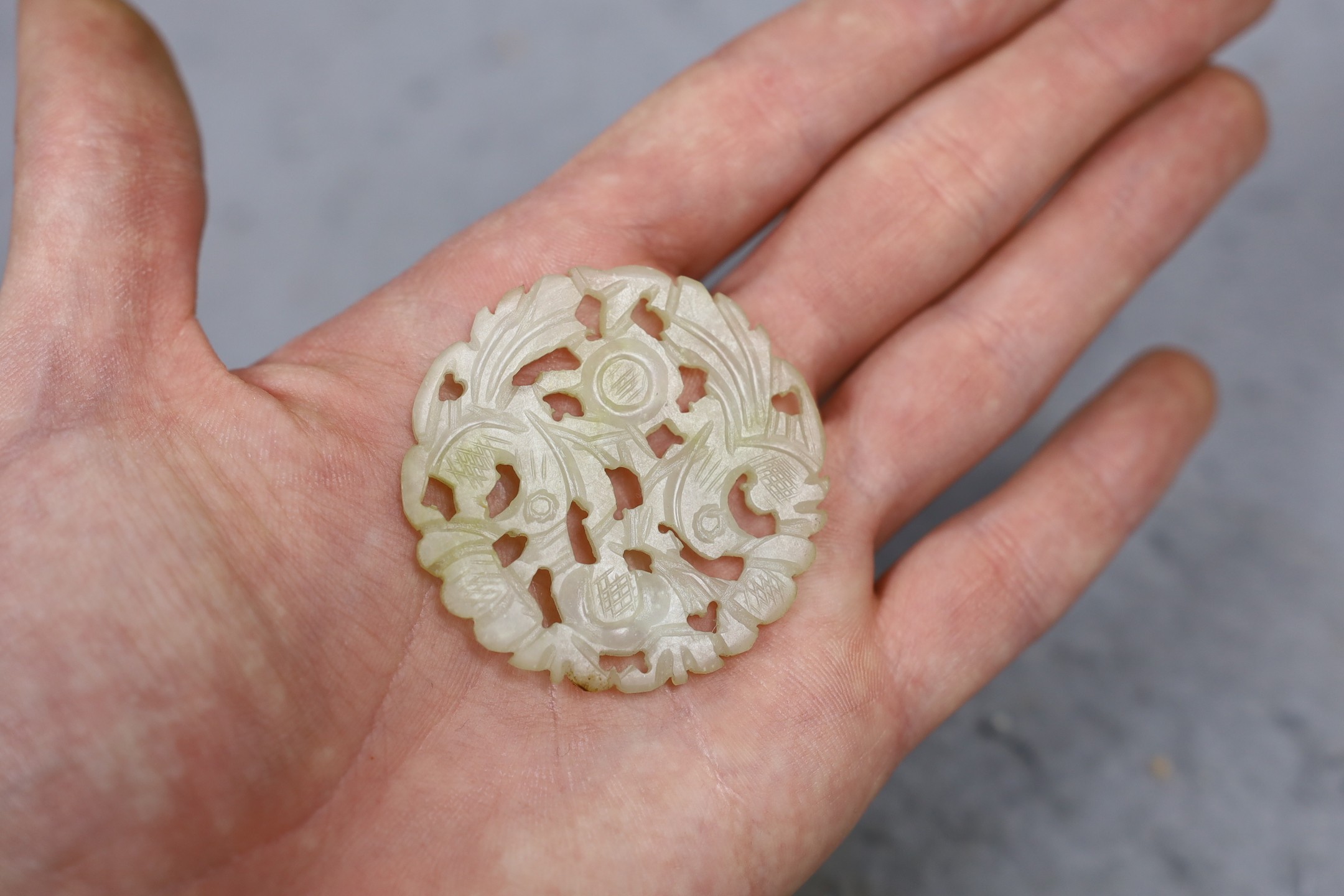 A Chinese jade disc and wood stand, 9cms high